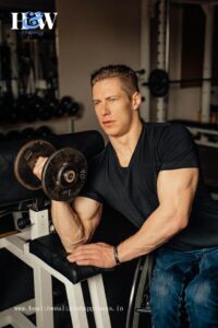 Fitness enthusiast performing Dumbbell Preacher Curls, seated with elbows supported on a bench